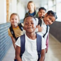 Portrait of a group of young children standing in a line in the hallway of a school